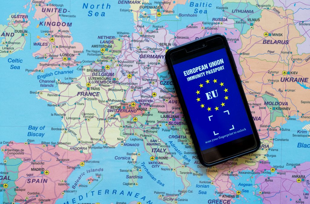 En smartphone, der viser et europæisk pasomslag på sin skærm, liggende på et kort med forskellige europæiske lande, herunder Frankrig, Tyskland, Storbritannien og Rusland.