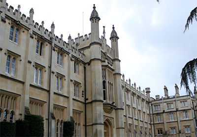 En majestætisk universitetsbygning i gotisk stil med spidse buer, skulpturelle facader og talrige høje vinduer, sat mod en overskyet himmel.
